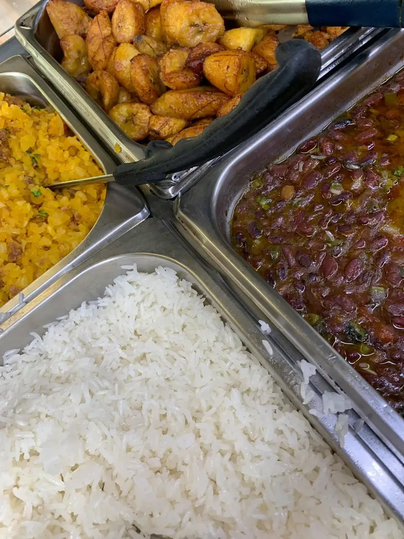 Bandejas del buffet con plátano maduro frito, arroz blanco, arroz con maíz y frijoles