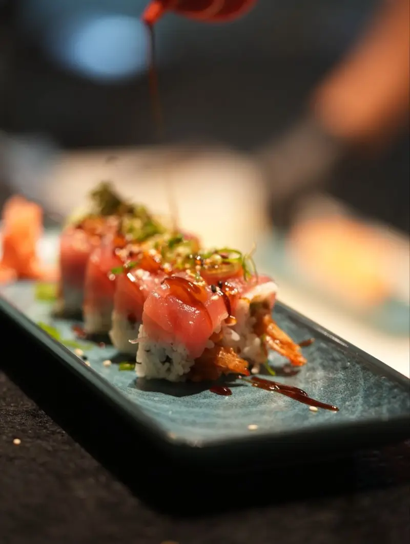 Big Kahuna roll cubierto de atún con salsa unagi, servido en un plato azul