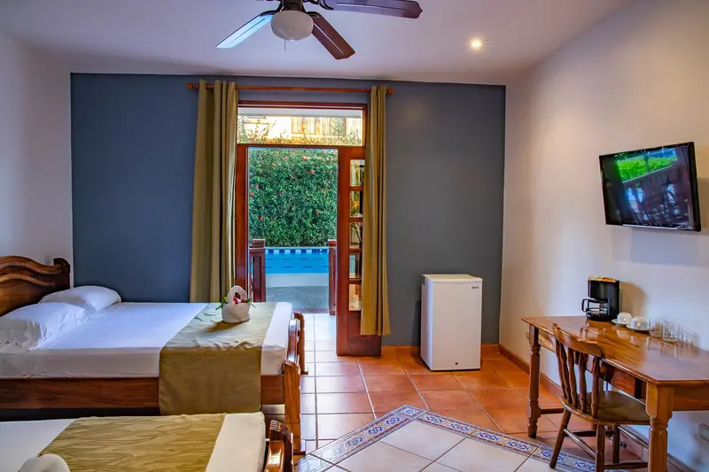 Habitación con una cama, ventilador de techo y puerta de vidrio hacia la terraza