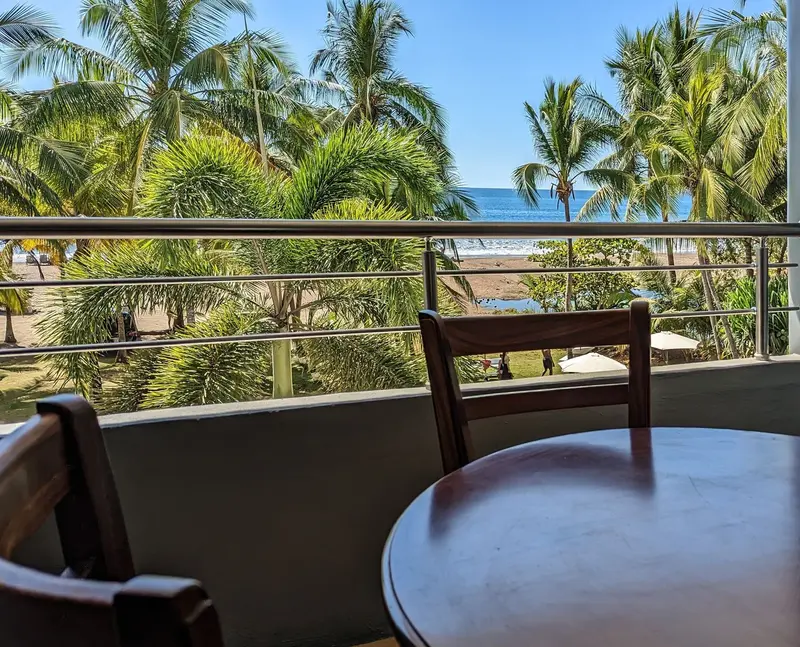 Balcón con mesa y silla frente a las palmeras y el mar