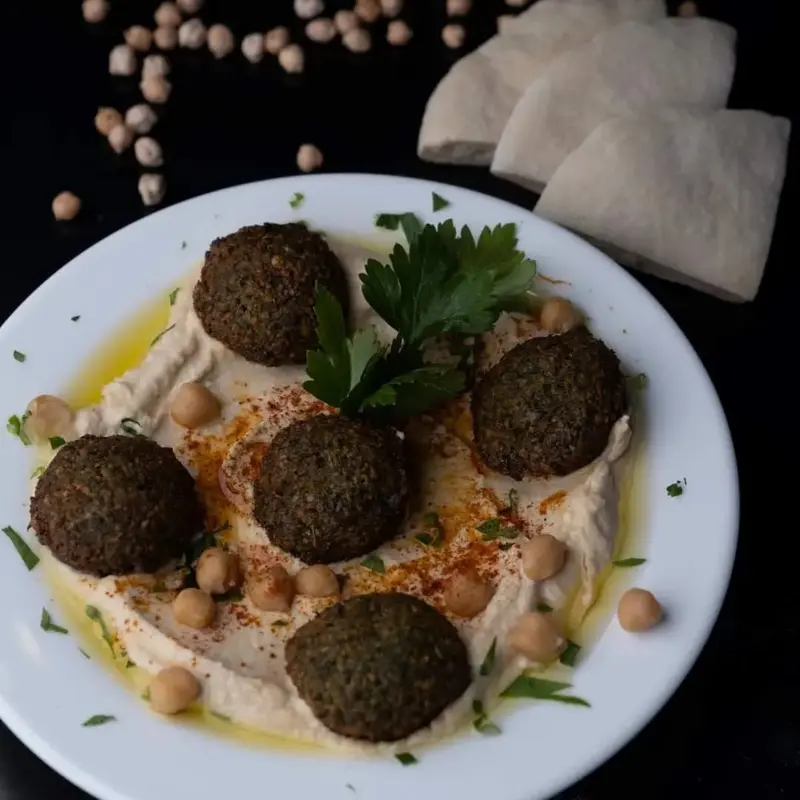 Plato de hummus con cinco bolitas de falafel, garbanzos y pan pita