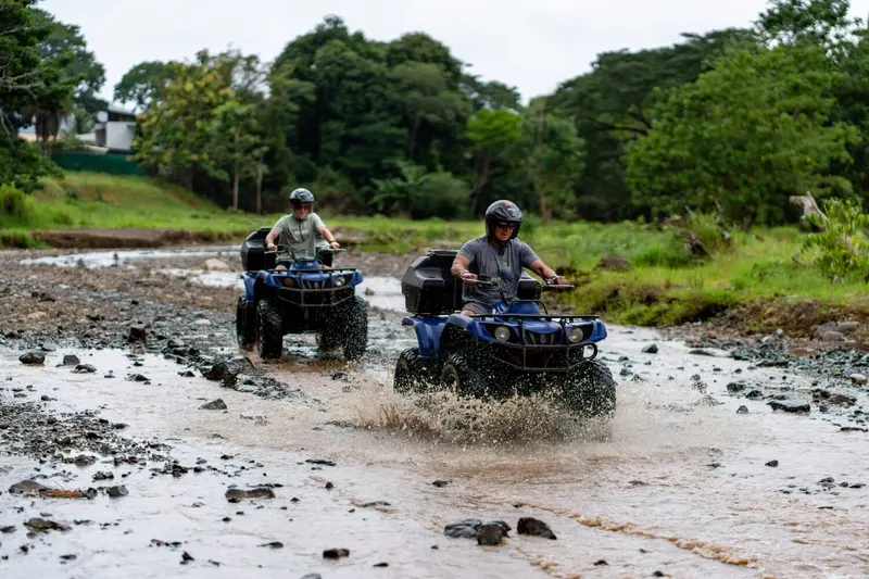 Dos conductores de ATV cruzando un río poco profundo