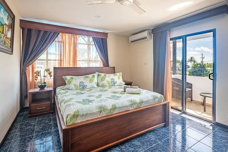 Habitación con cama king de madera, balcón y piso de baldosas azules