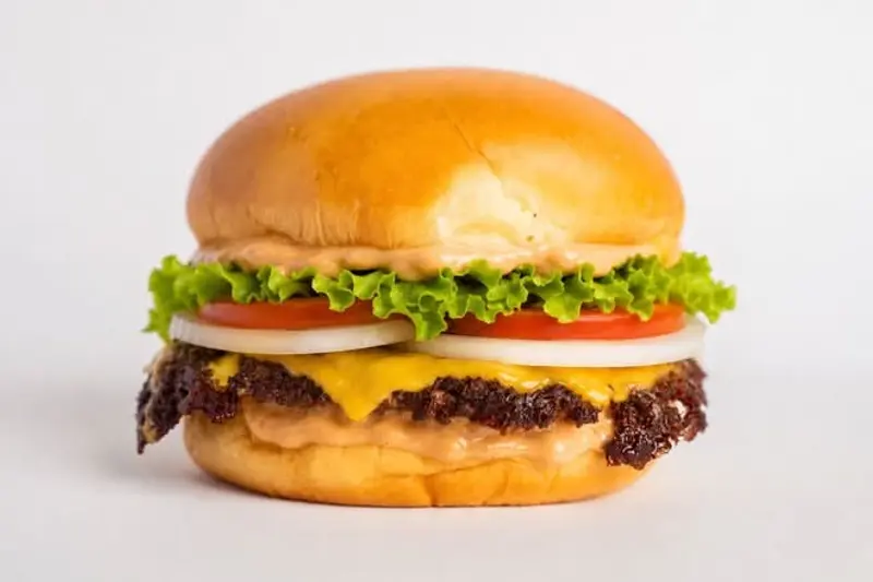 Classic Burger con lechuga, tomate, cebolla y queso americano derretido sobre pan brioche