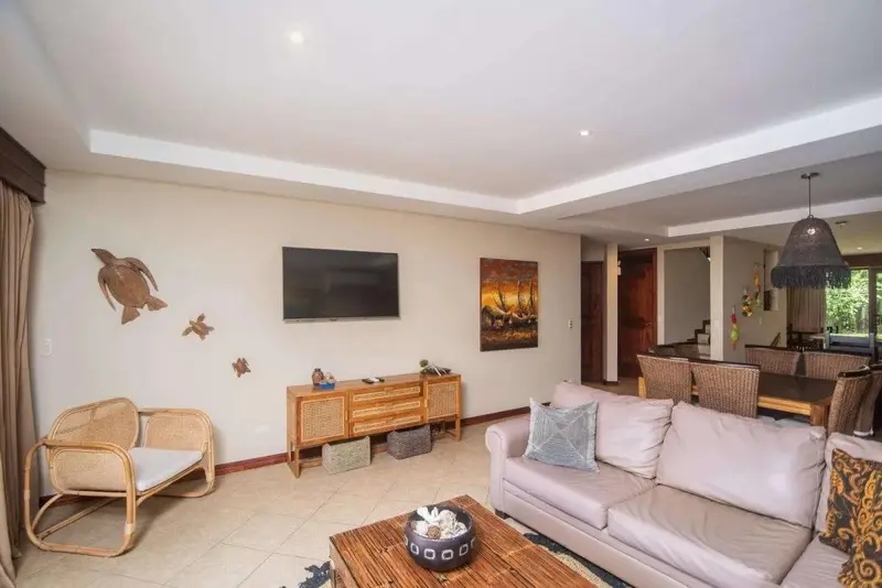 Sala con sofá, televisor y comedor al fondo