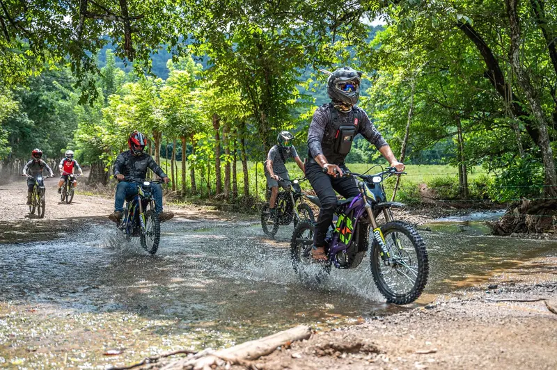 Moto eléctrica de enduro con su piloto cruzando una quebrada entre árboles