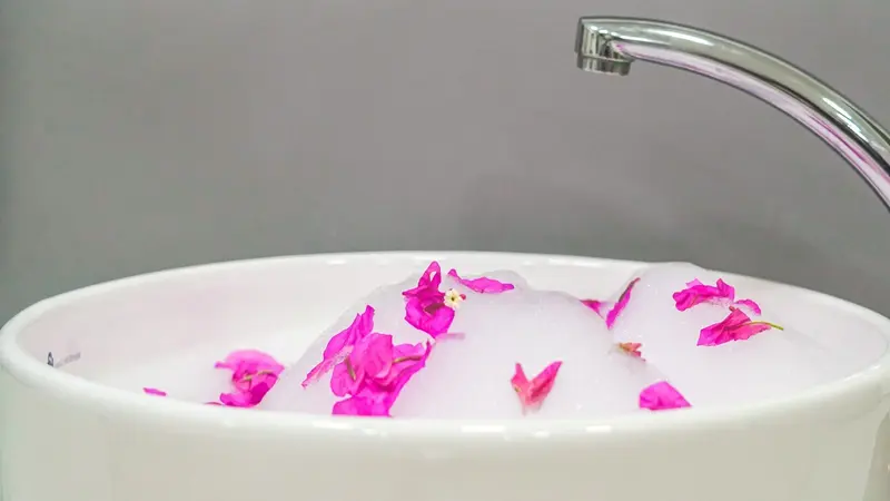 Pediluvio blanco con espuma y pétalos rosados