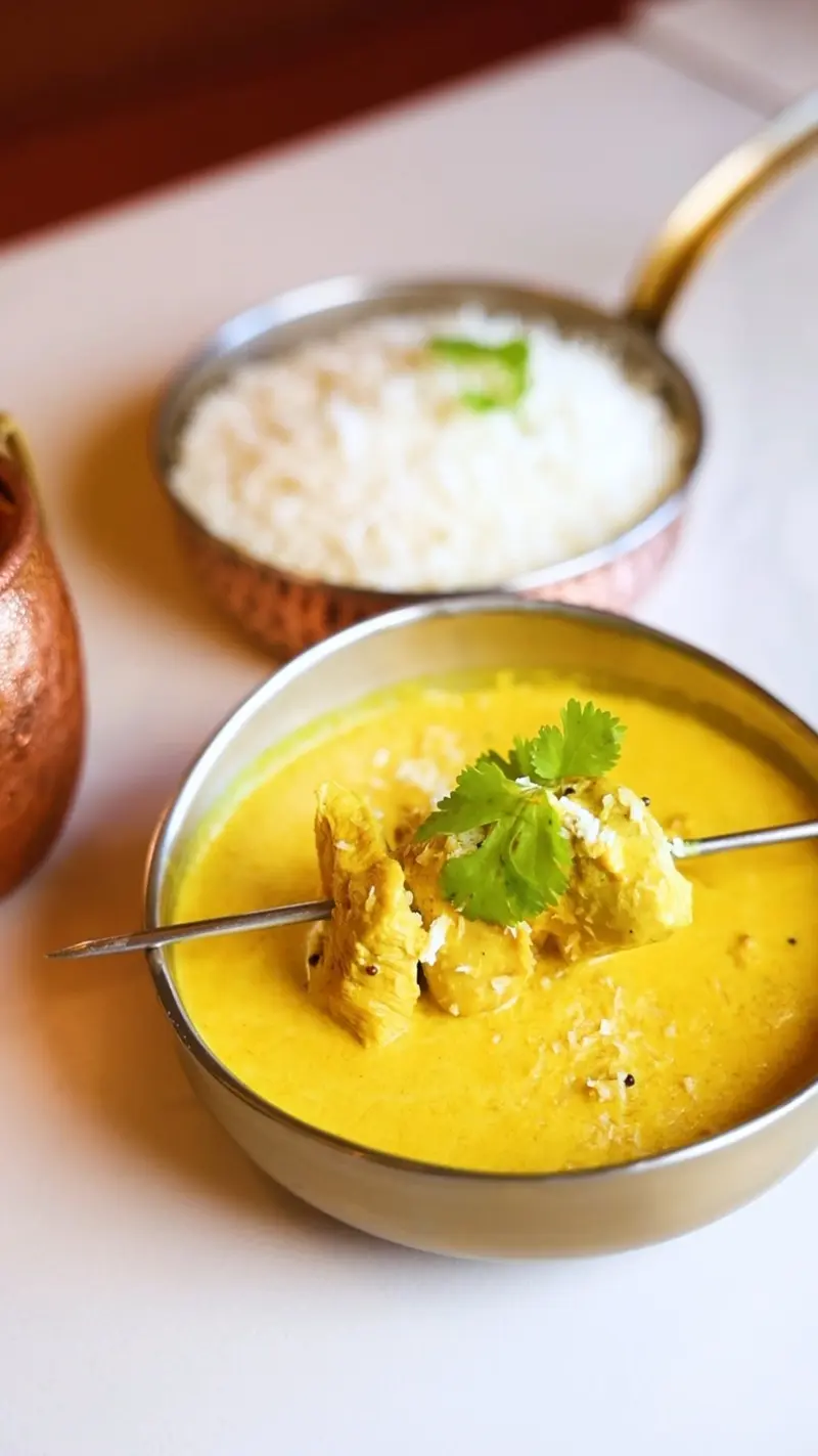 Curry amarillo con cilantro en un cuenco de metal junto a un tazón de arroz basmati