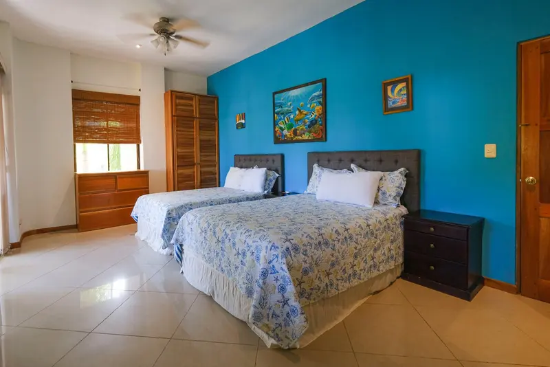 Habitación con dos camas y una pared azul con cuadros de peces