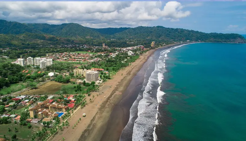 Vista aérea de la playa de Jacó, con la costa, el oleaje y los edificios frente al mar