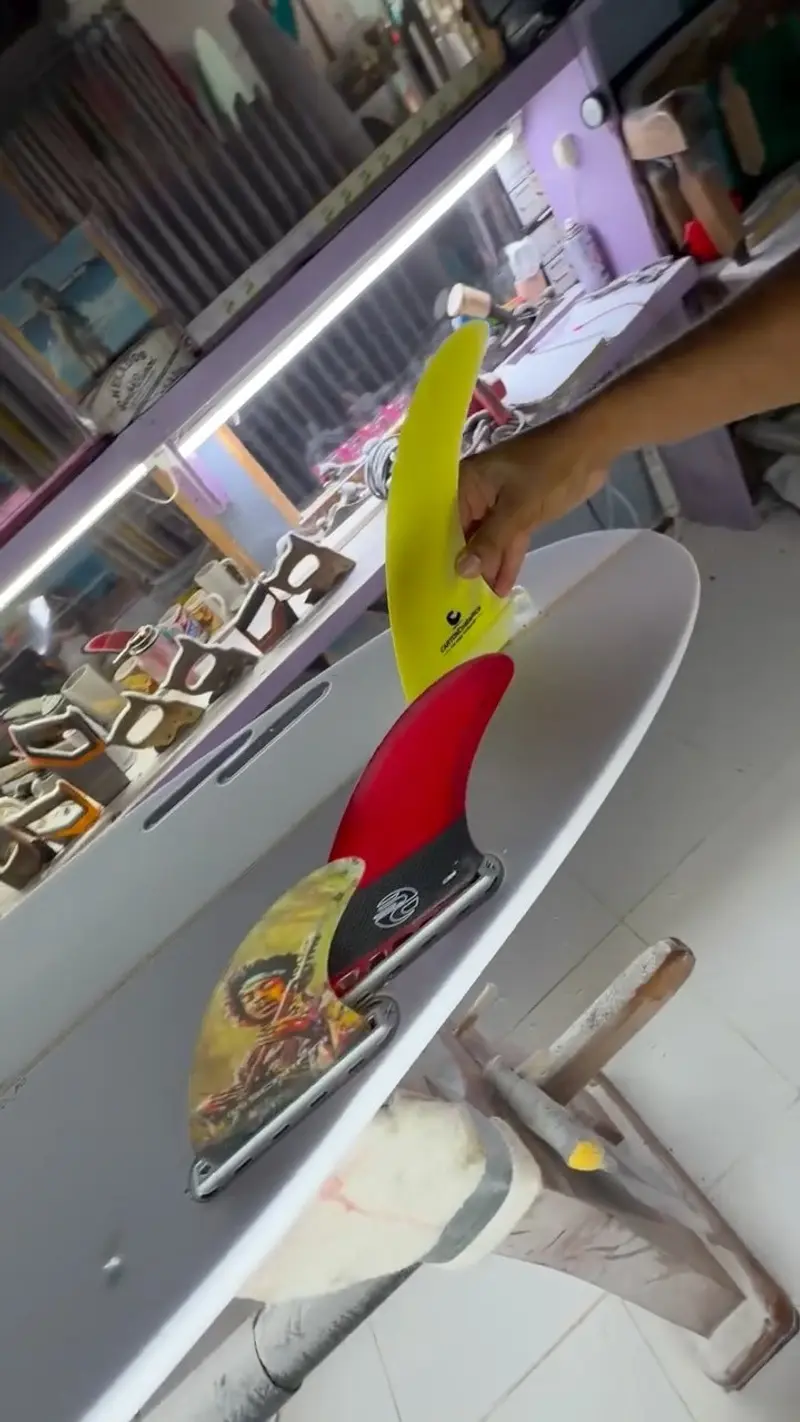 Mano colocando una aleta amarilla y roja en una tabla blanca sobre el soporte de trabajo