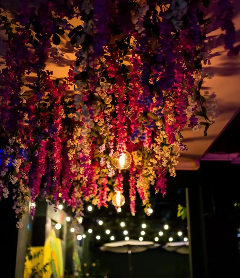 Terraza lounge con flores colgantes violetas y luces cálidas de noche