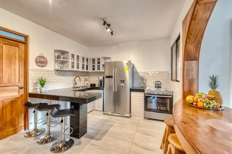 Cocina de madera con isla y taburetes en la villa Casa Amen