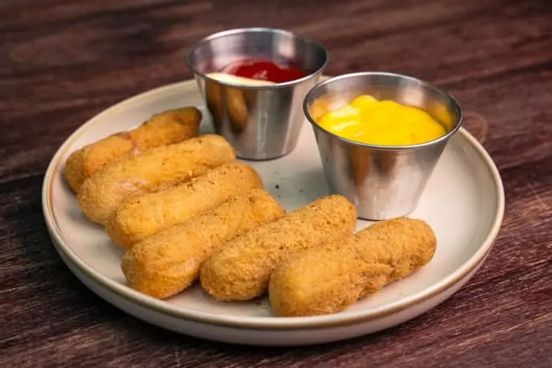 Palitos de queso empanizados con pocillos de ketchup y mayonesa especial sobre un plato