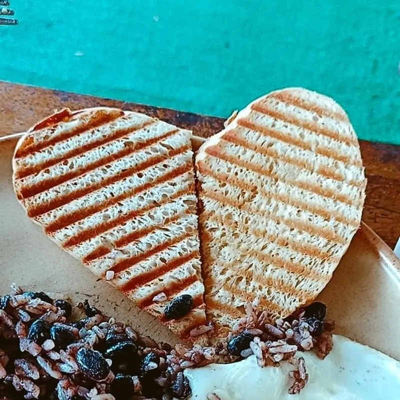 Sándwich prensado en forma de corazón sobre un plato turquesa