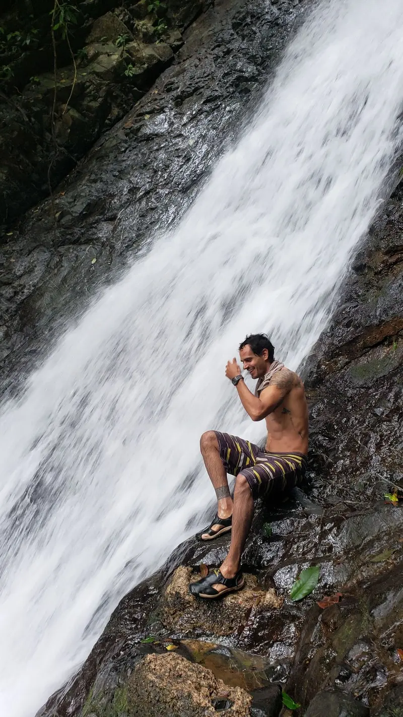 Hombre sentado sobre una roca junto a una gran cascada