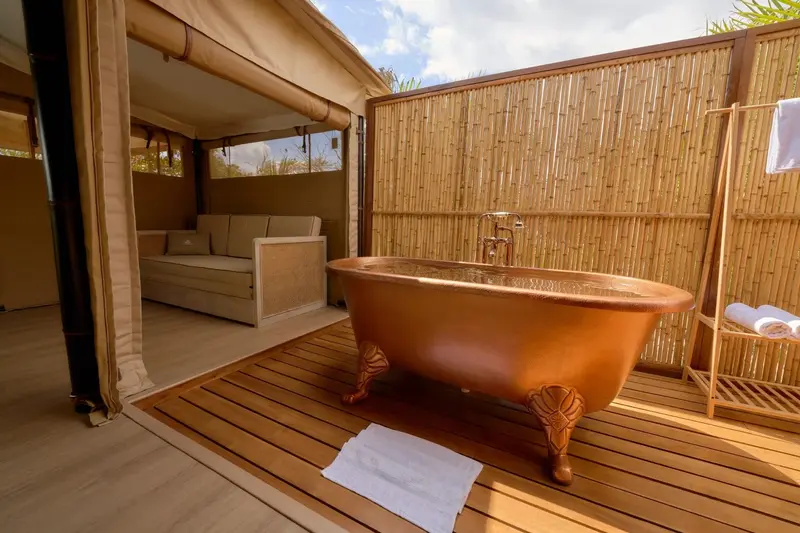 Bañera de cobre exterior en una villa, rodeada de paredes de bambú