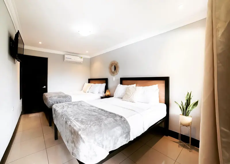 Habitación privada con dos camas de cabecera de madera y televisor