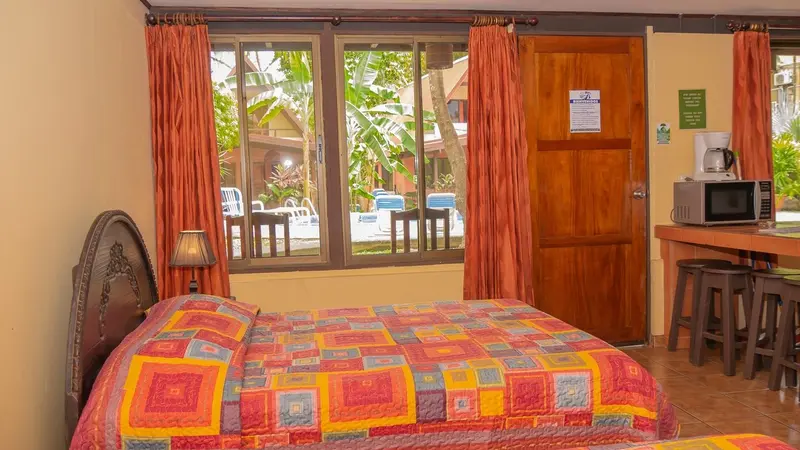 Habitación con cama doble, ventana con vista al jardín y una mesa con microondas