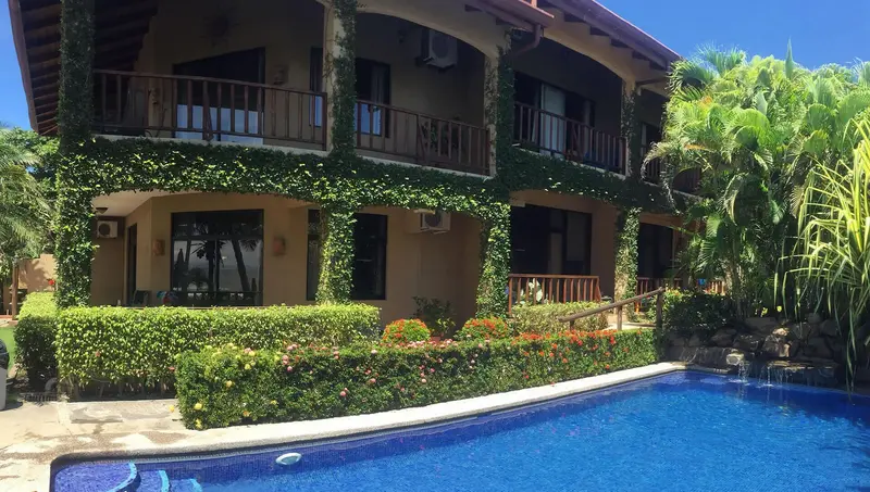 Hotel building surrounded by garden, next to the pool