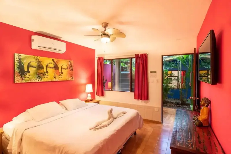 Habitación con paredes rojas, cama grande y pinturas de Buda