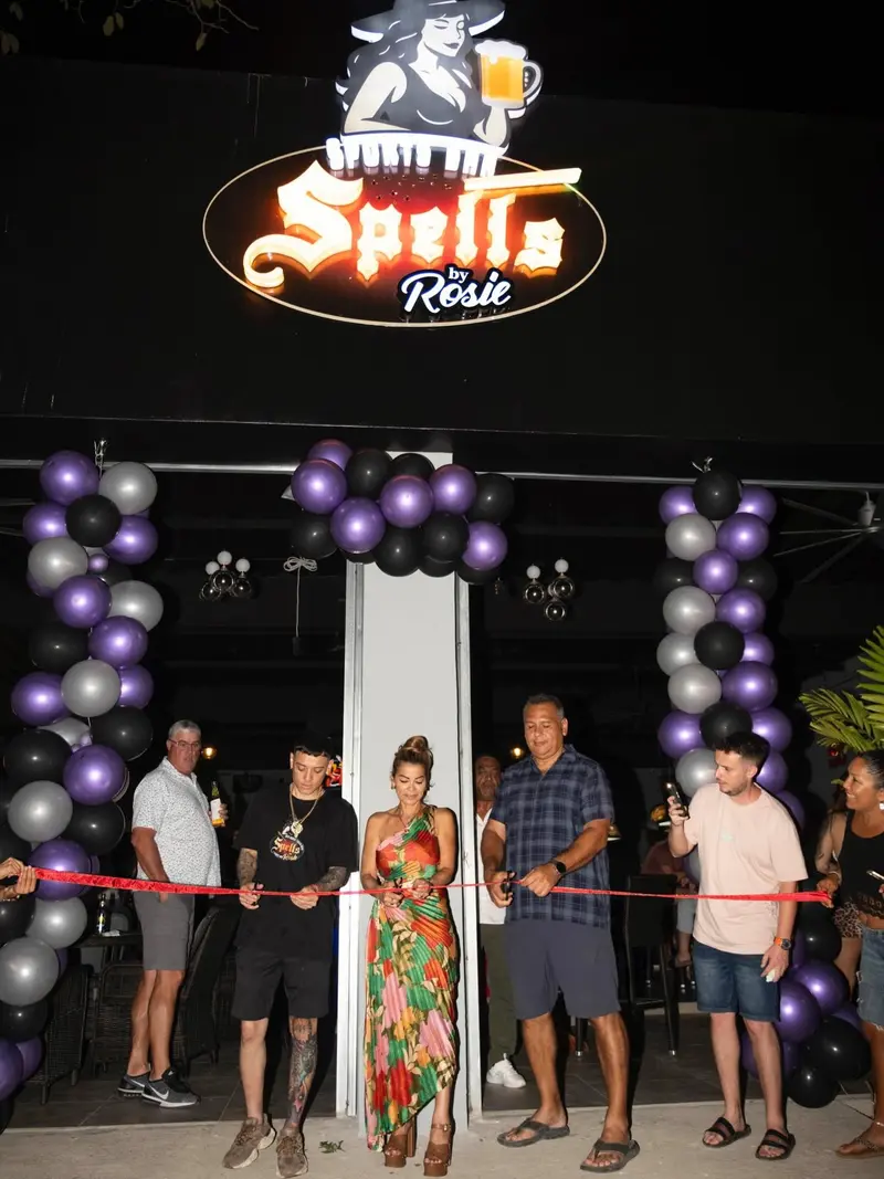 Corte de cinta en la entrada de Spells durante la noche de inauguración, con el rótulo y globos negros y plateados