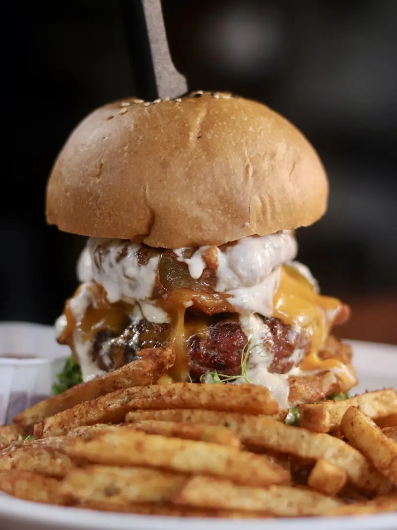 Hamburguesa con queso cheddar derretido, tocino y papas fritas con cajún