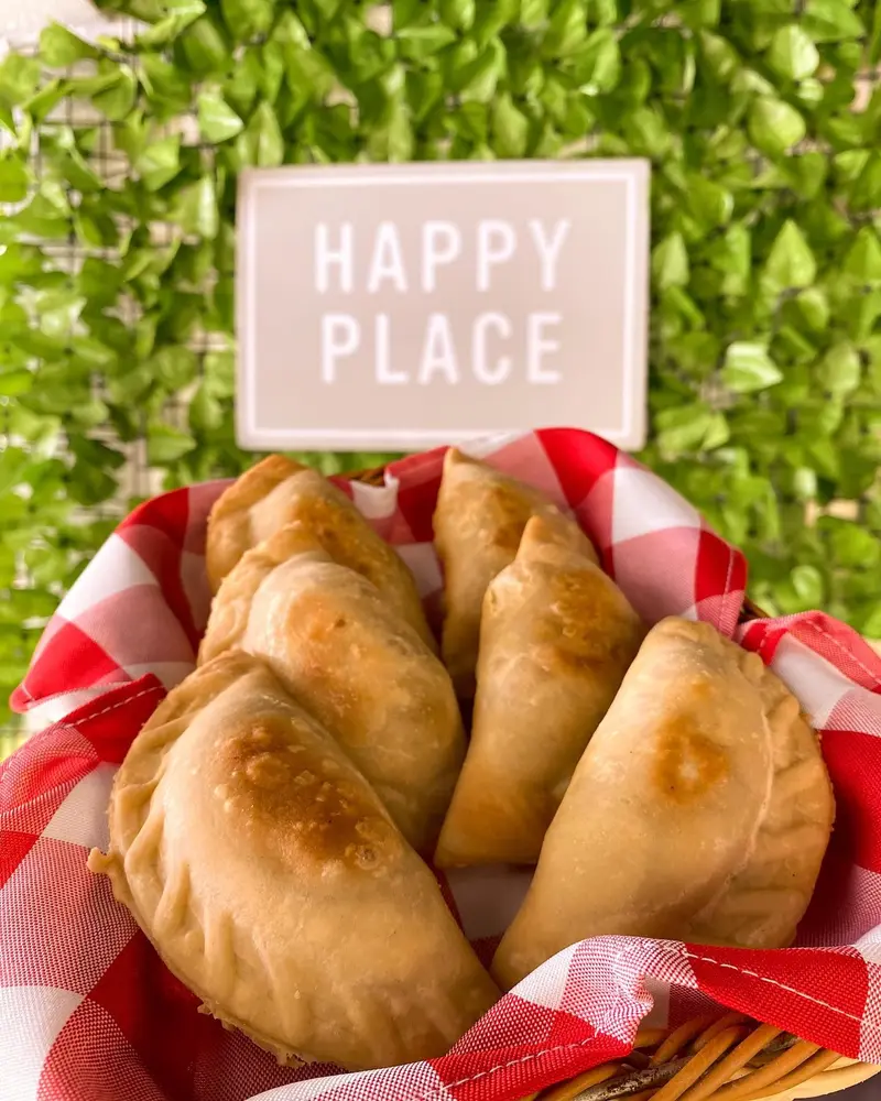 Cesta con empanadas doradas sobre un mantel de cuadros rojos y blancos