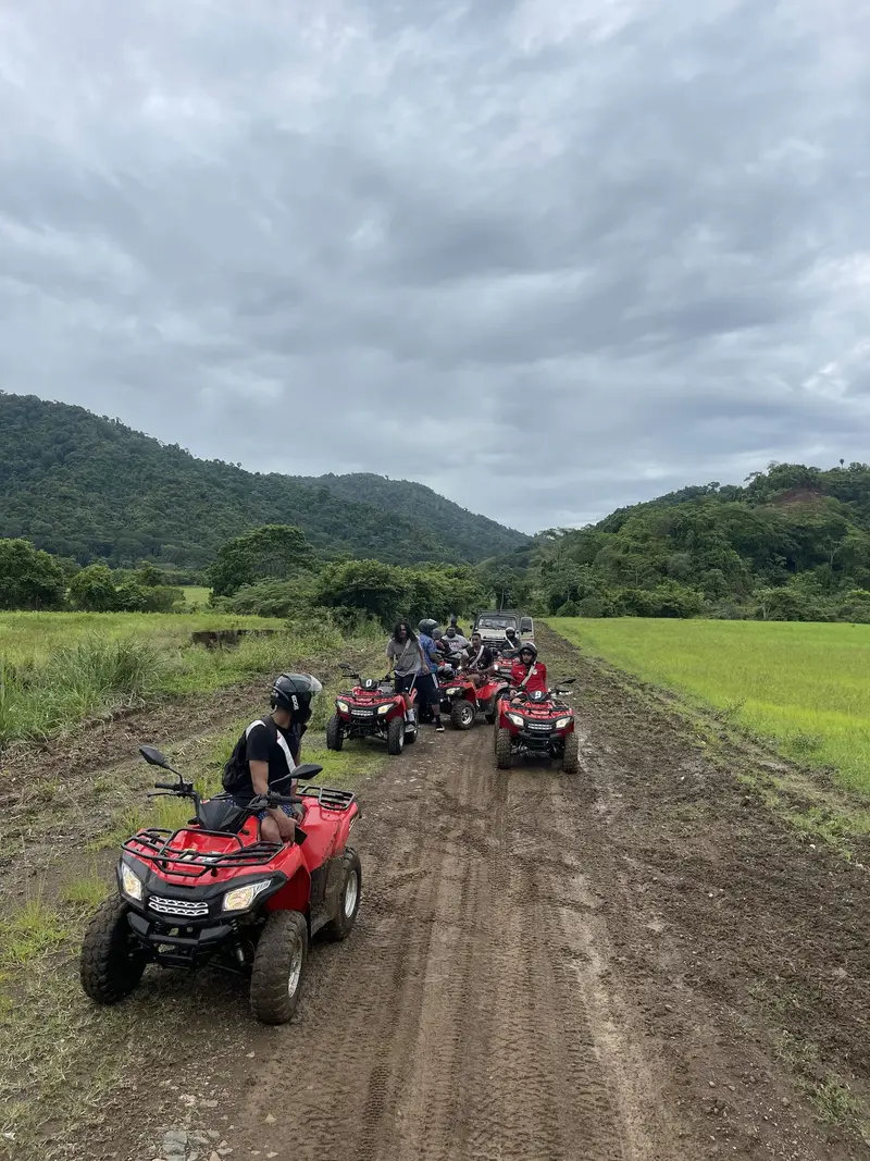 Grupo de cuatrimotos rojas por un camino de tierra entre campos verdes y montañas