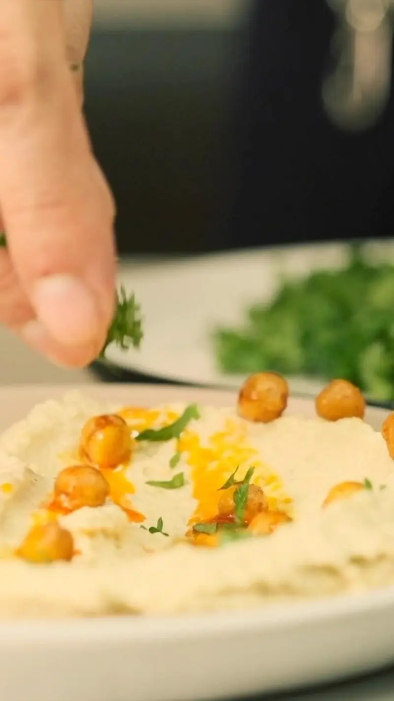 Hummus topped with roasted chickpeas and herbs