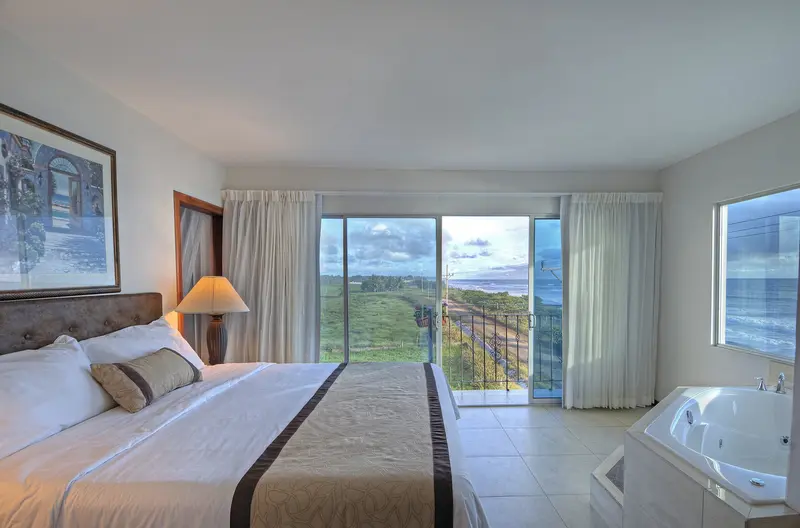 Suite with a large bed, a whirlpool tub and a balcony with an outdoor view