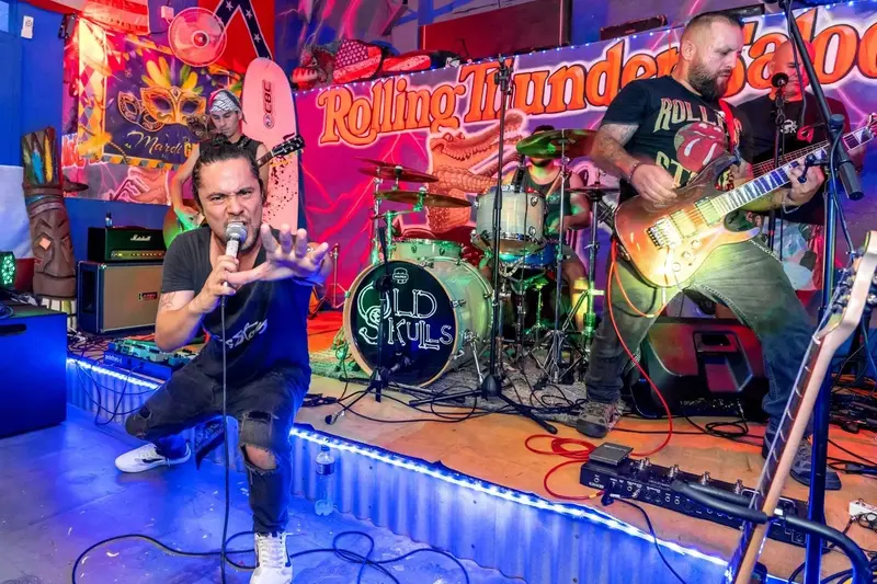 Banda tocando en el escenario del bar, con el cantante inclinado al frente y un guitarrista