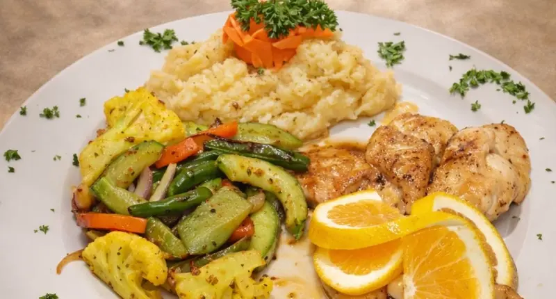 Pollo a la naranja con puré, vegetales salteados y gajos de naranja
