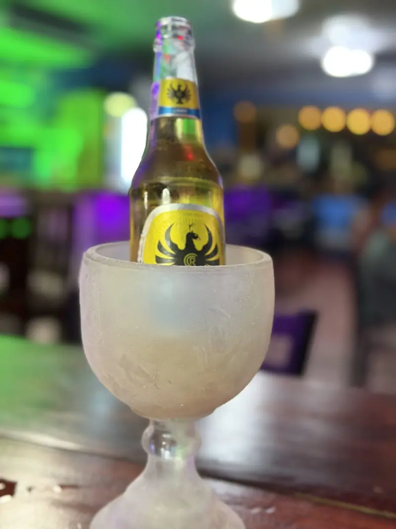Botella de cerveza en una copa escarchada sobre la barra