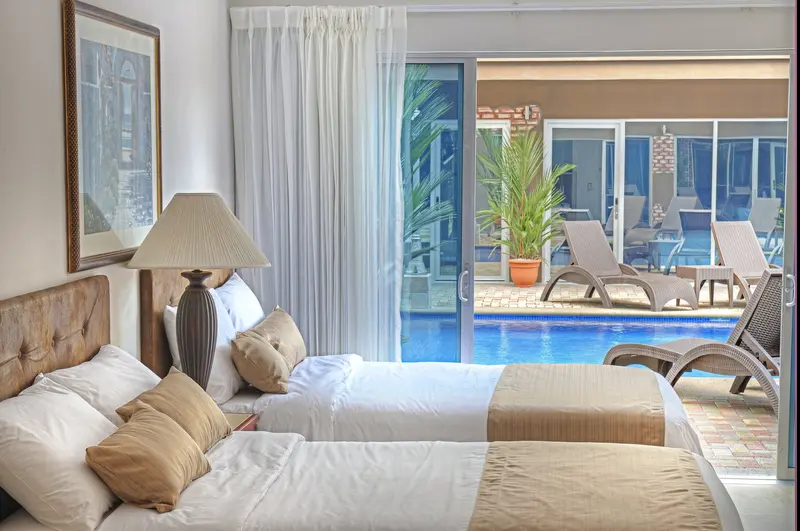 Room with two double beds and a large window overlooking the pool
