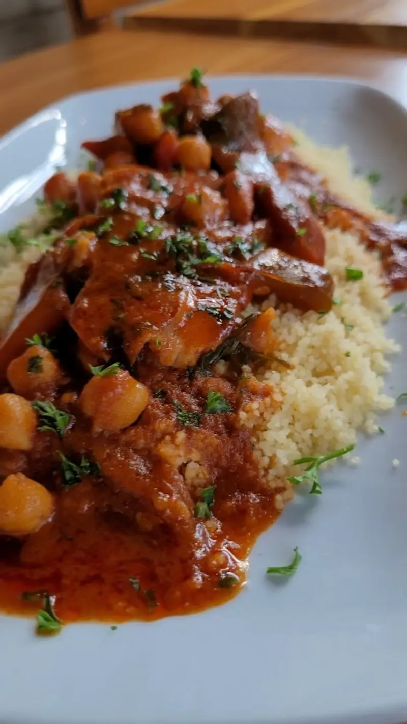 Guiso de garbanzos y carne sobre cuscús en un plato blanco