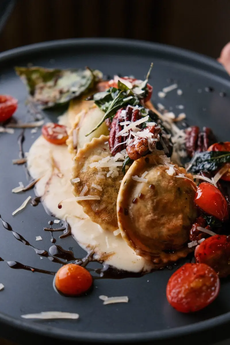 Plato con raviolis, salsa cremosa, tomates cherry y queso rallado