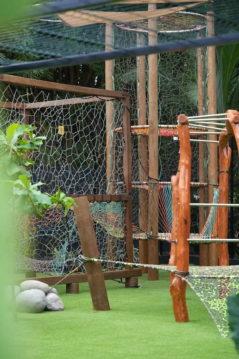 Área de juegos para niños con estructura de madera y red sobre césped