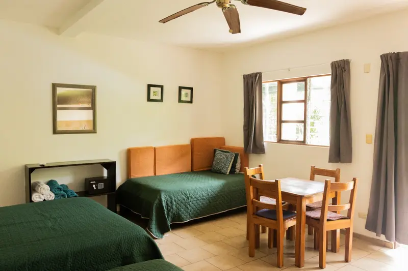 Habitación con sofá cama, mesa de comedor de madera con sillas y una ventana