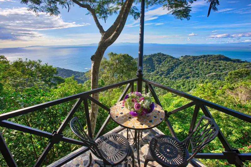 Terraza con barandal de madera y vista al bosque tropical y al océano Pacífico