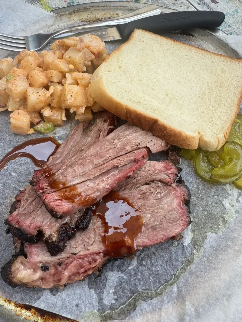 Lonjas de brisket con salsa, ensalada de papa, pan blanco y pepinillos