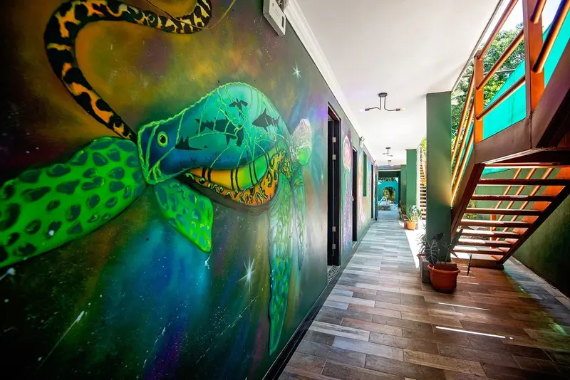 Pasillo con mural de tortuga verde y escalera de madera
