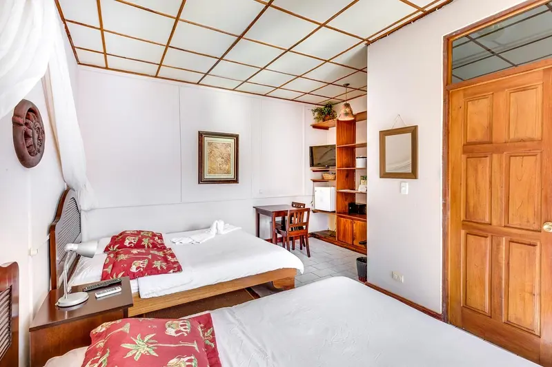 Habitación con camas, un cuadro en la pared, estantes y una puerta de madera