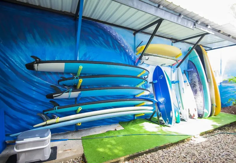 Rincón de descanso con sofás y tablas de surf azules apiladas en una pared