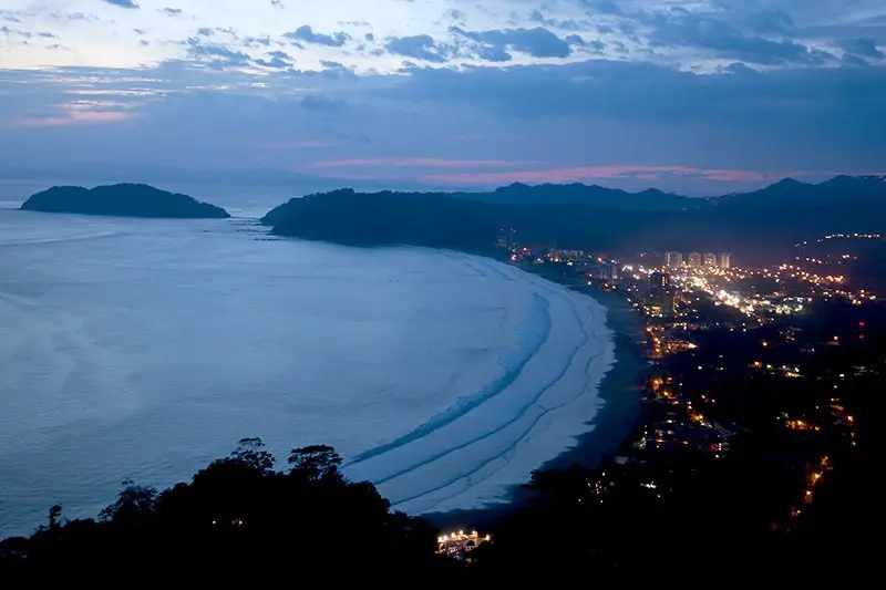 Vista nocturna de la bahía de Jacó con las luces del pueblo y el mar al fondo