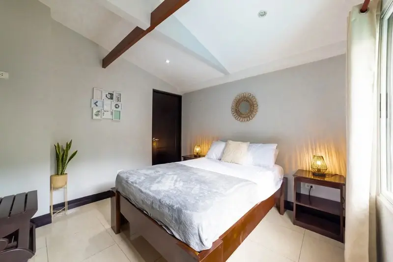 Habitación con cama queen, lámpara de pared y cielo raso de madera