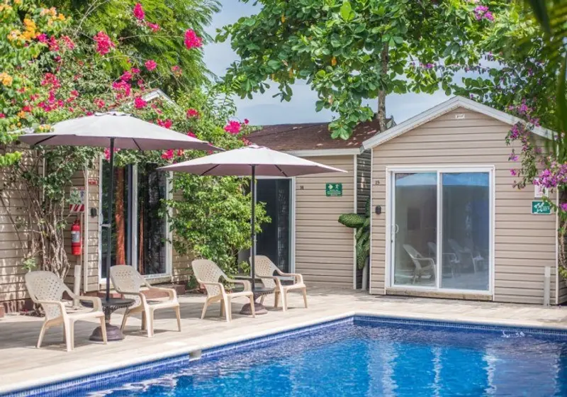 Habitaciones con puerta corrediza de vidrio frente a la piscina, con sillas y sombrillas