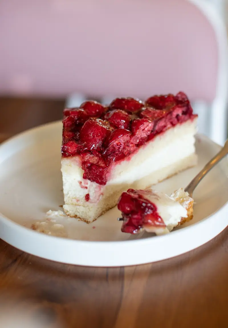 Rebanada de cheesecake con frambuesas sobre un plato blanco