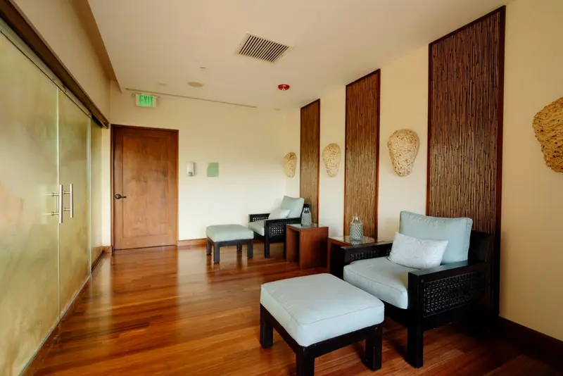 Sala de espera con sillones, otomanas y paneles de bambú