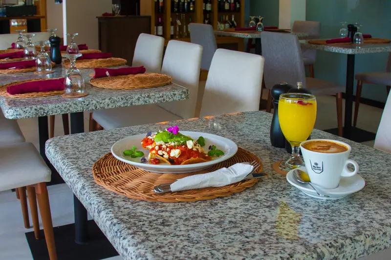 Desayuno en una mesa de granito: plato con ensalada, jugo de naranja y café con leche